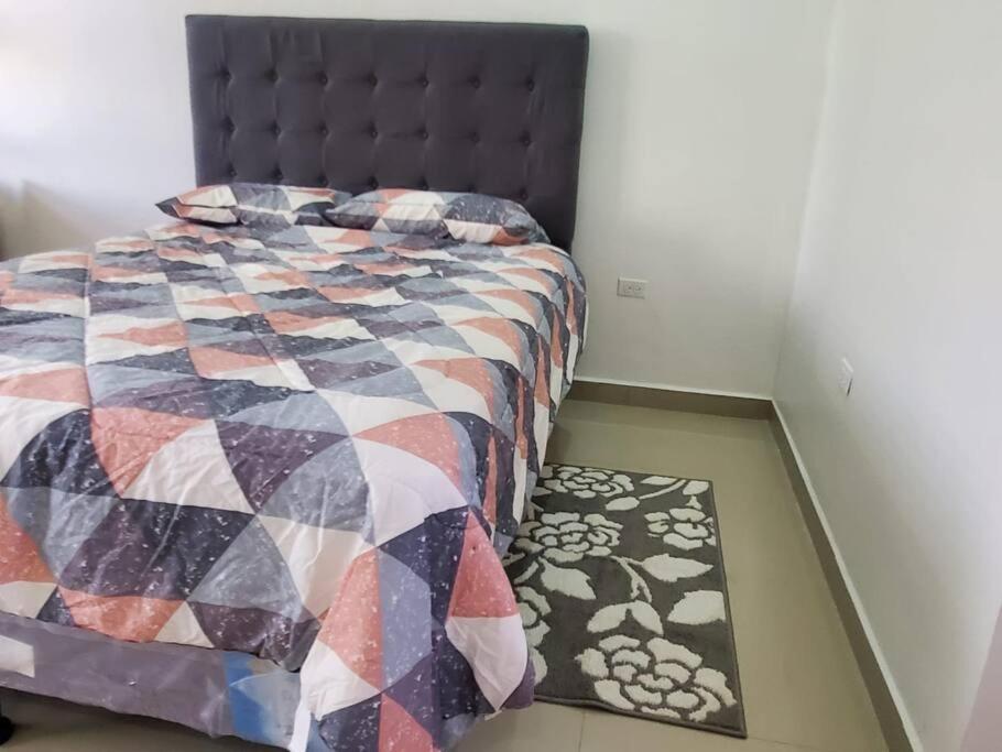 ein Schlafzimmer mit einem Bett mit einer Decke und einem Teppich in der Unterkunft Apartamentos y Hostal Rudon # 5 in Puerto Cortes