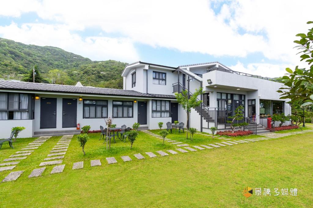 una casa blanca con césped delante en Bi La Homestay en Luye