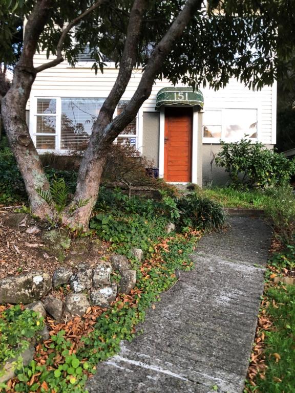 czerwone drzwi na białym domu z drzewem w obiekcie Close To Nature & City w mieście Wellington