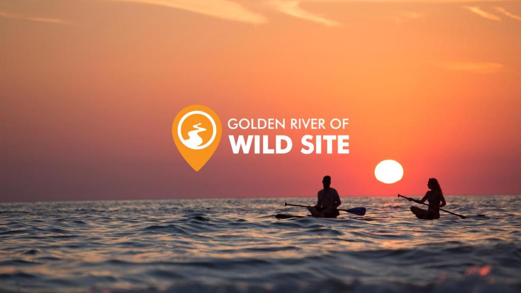 two people sitting in the ocean watching the sunset at Golden River of wild side in Bhurkīā