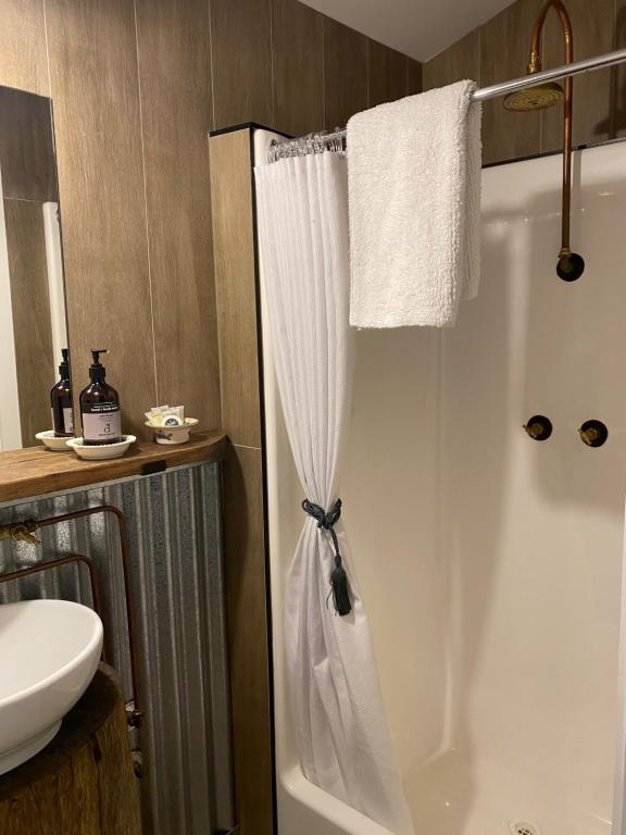 La salle de bains est pourvue d'une douche avec rideau de douche blanc. dans l'établissement Holly House Garden Studio, à Moyhu