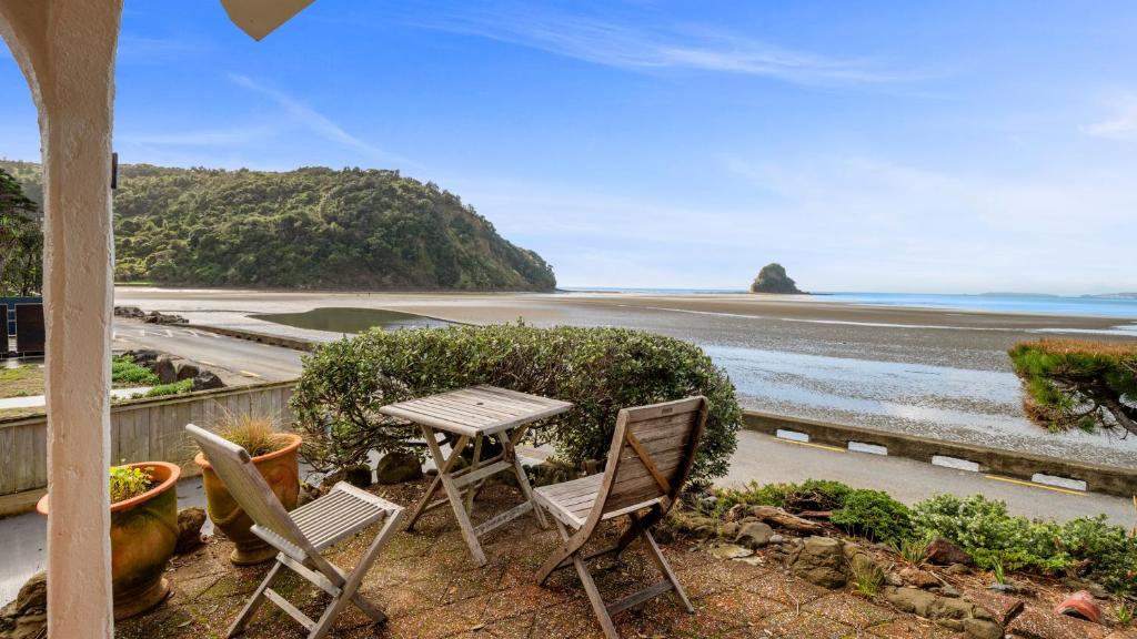 a table and chairs on a balcony with a view of the beach at Beachside Bliss - Waiwera Beachfront Holiday Home in Orewa
