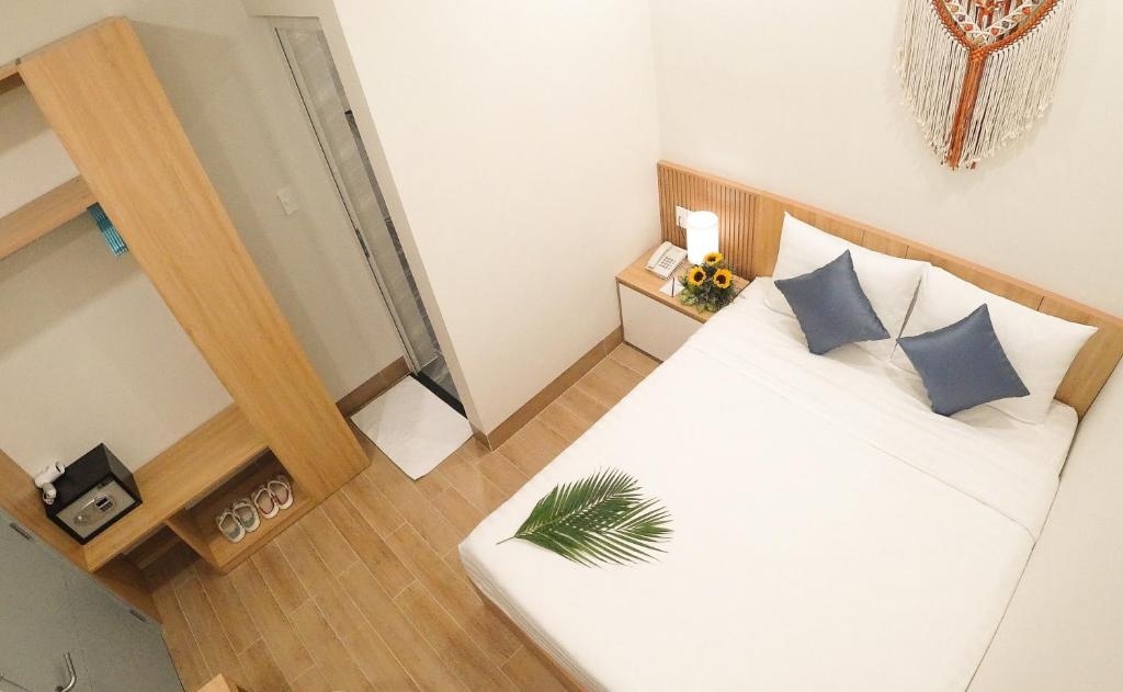 Dormitorio pequeño con cama blanca y almohadas azules en Vy's House Phanthiet Hotel, en Ấp Tân An (1)