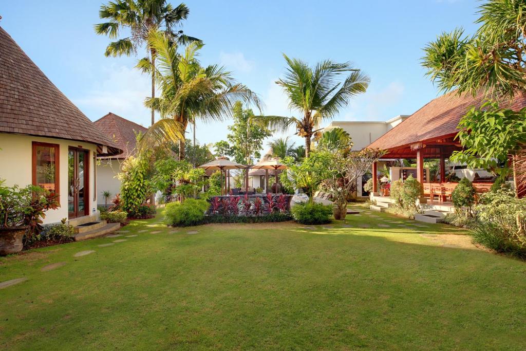 een tuin met palmbomen en een huis bij Kandahill Bali in Uluwatu