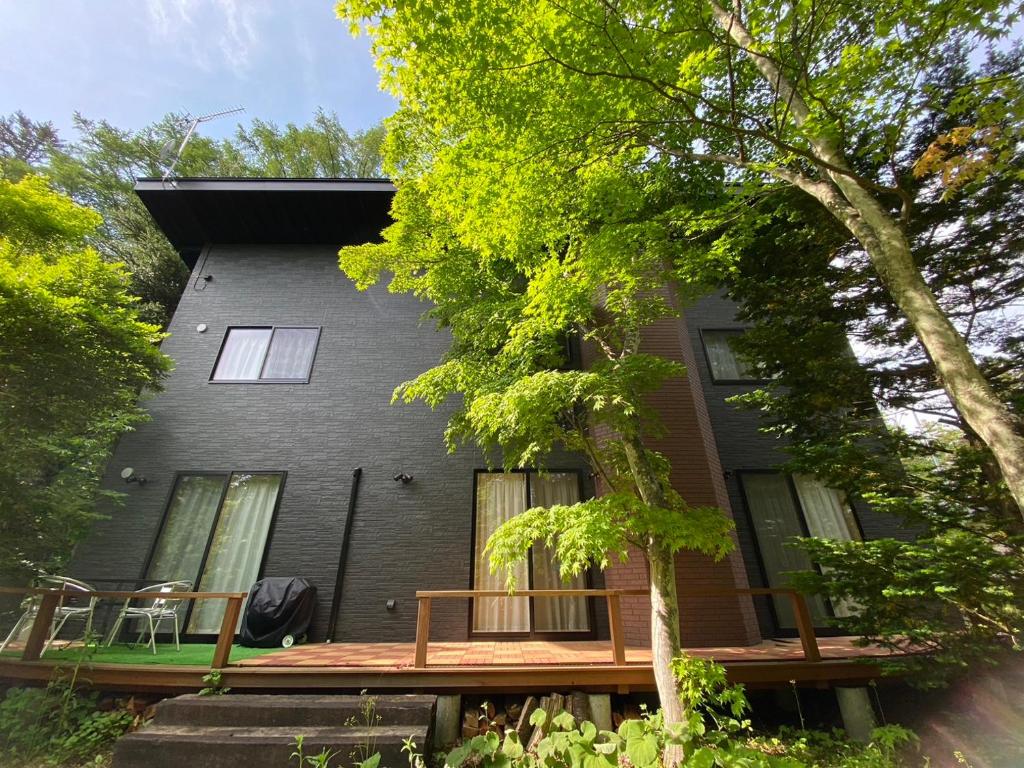 a black house with a porch and a deck at 木漏れ日ハウス in Karuizawa