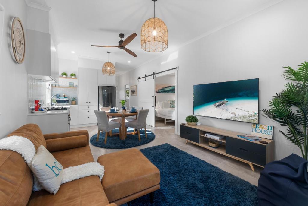 a living room with a couch and a tv and a table at Dicky Beach Original - 2 Bed Downstairs Studio 200m to Beach in Caloundra