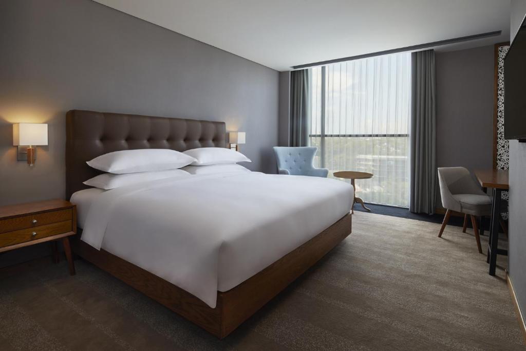 a hotel room with a large white bed and a desk at Four Points by Sheraton Balikpapan in Balikpapan