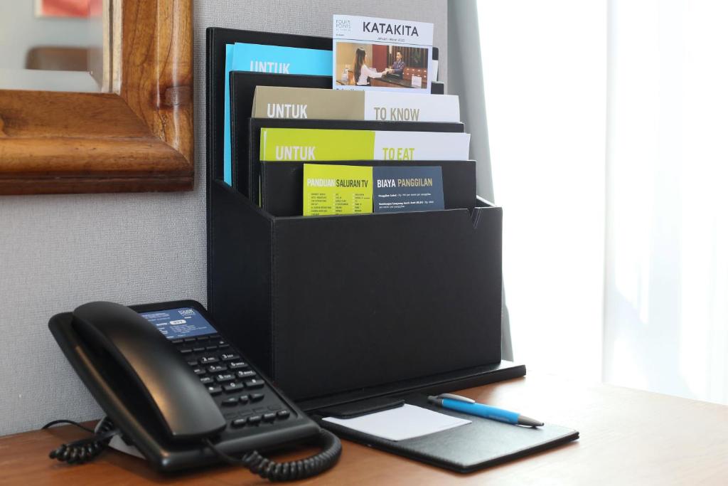 a phone sitting on a desk next to a book shelf at Four Points by Sheraton Balikpapan in Balikpapan