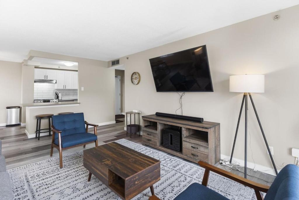 a living room with a tv and a couch and a table at Newly Renovated 2 Bedroom Downtown Saskatoon Condo in Saskatoon