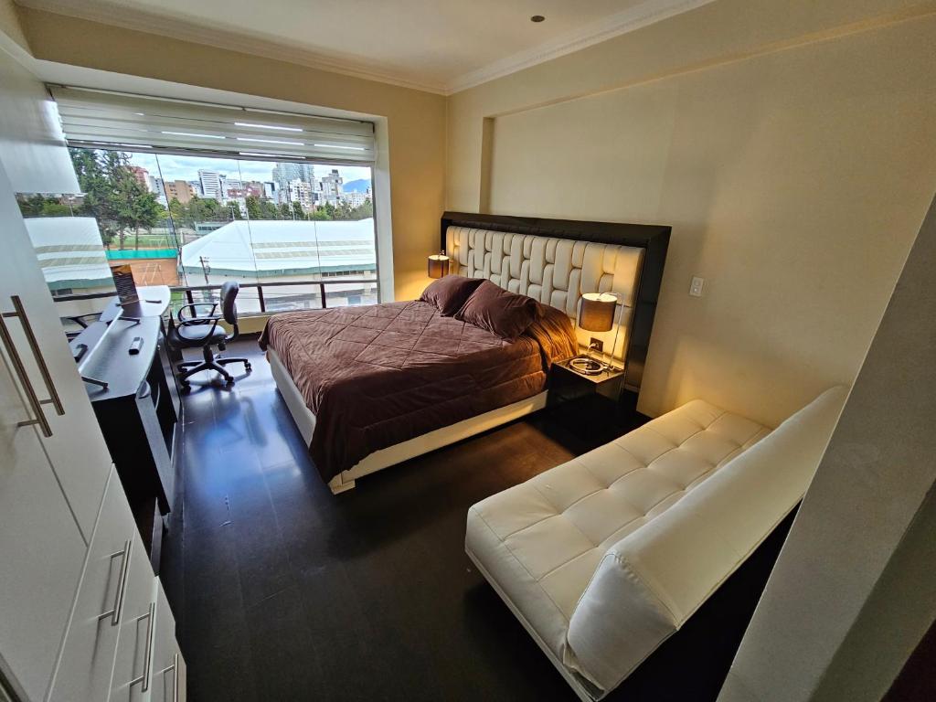 1 dormitorio con cama, sofá y ventana en Suite de lujo en excelente sector, netflix, disney plus, en Quito