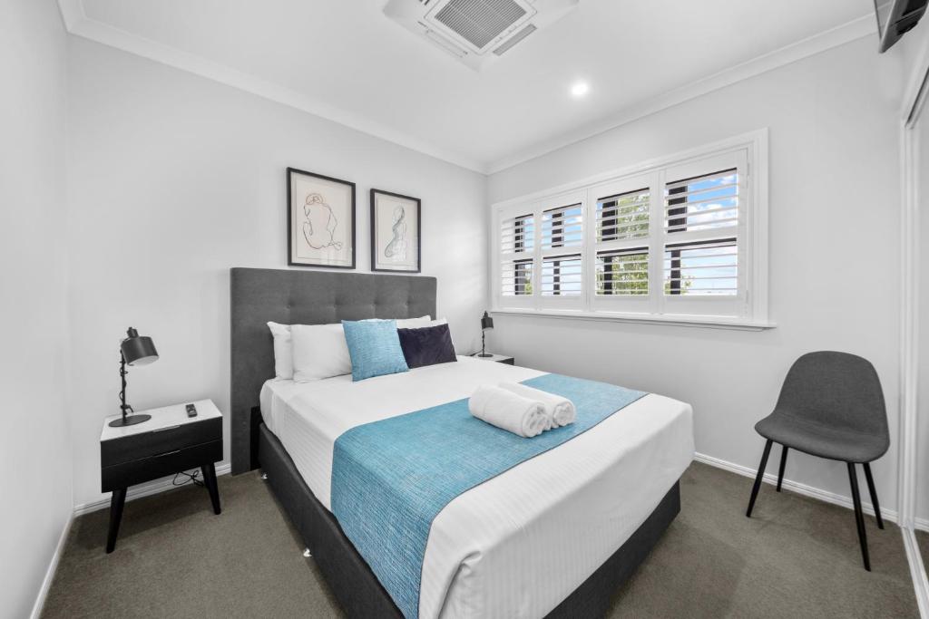 a bedroom with a bed and a chair in it at CocoBrew Boutique Apartments in Rockhampton