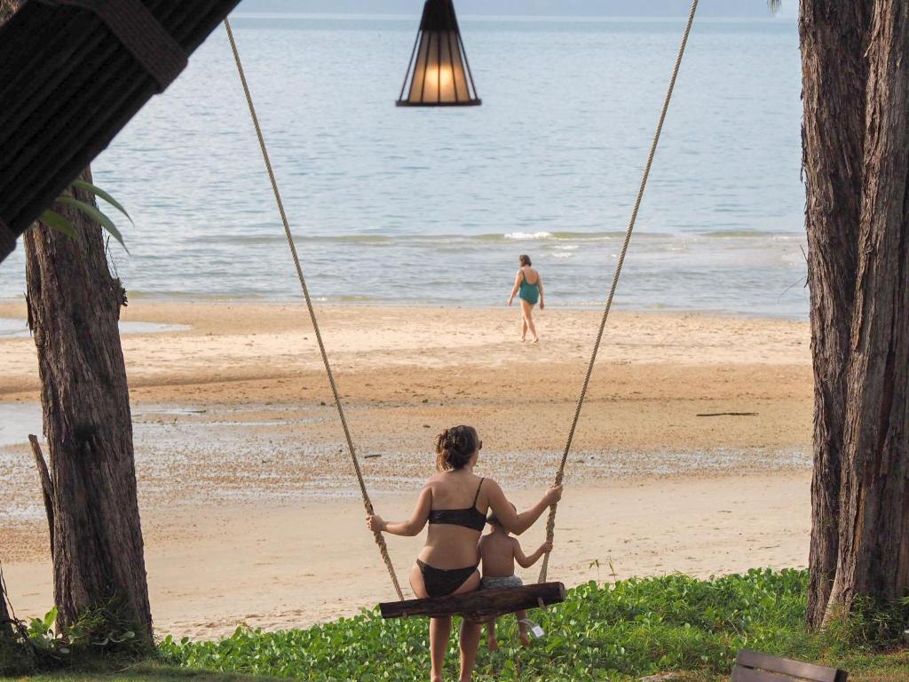 a woman in a bikini sitting on a swing at the beach at Anyavee Tubkaek Beach Resort in Tab Kaek Beach