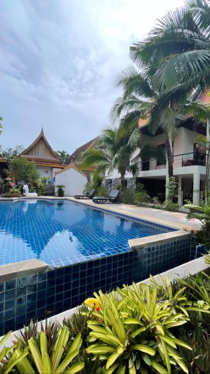 a large swimming pool in a resort with palm trees at Villa Aisawan in Phuket