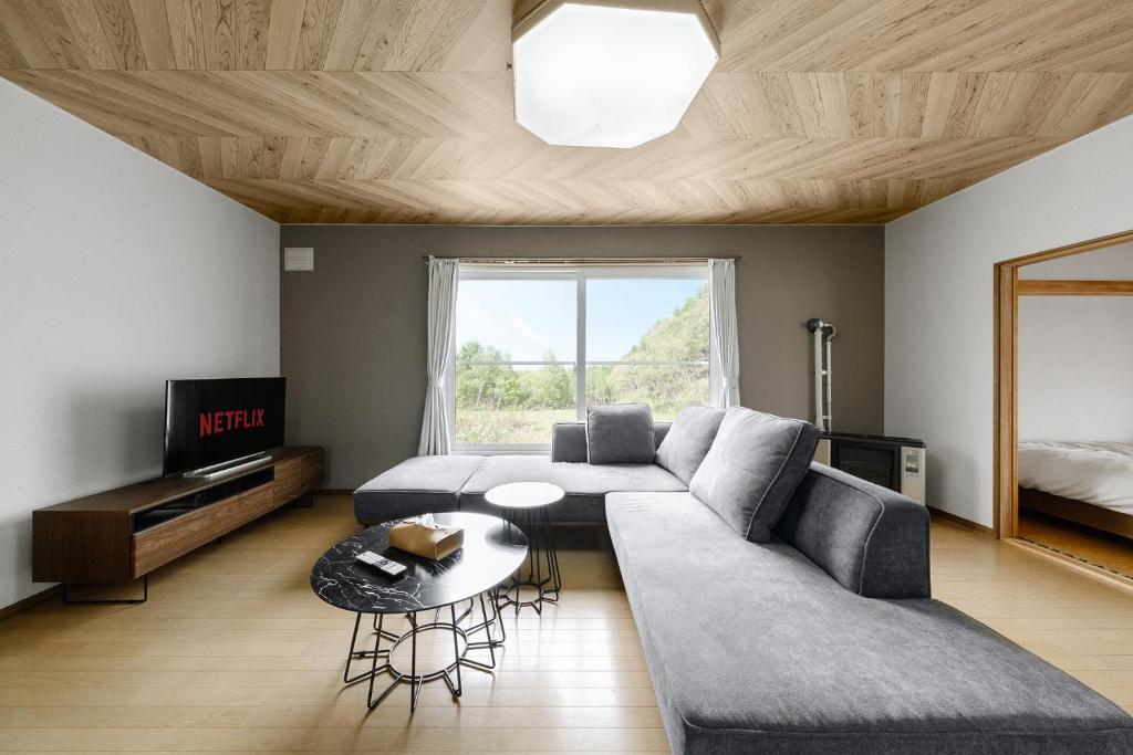 een woonkamer met een bank en een tafel bij Landmark Annex in Furano
