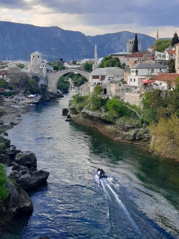 a boat in a river in a city with a bridge at Apartments Old Bridge in Mostar