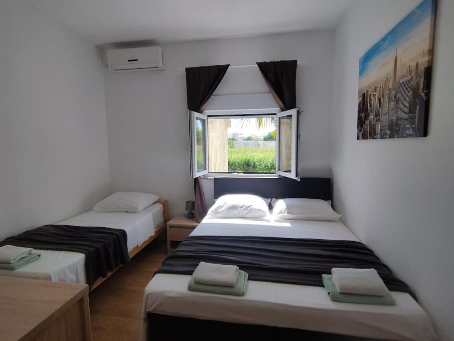 two beds in a room with a window at Apartment Bella Costa II. in Kaštela