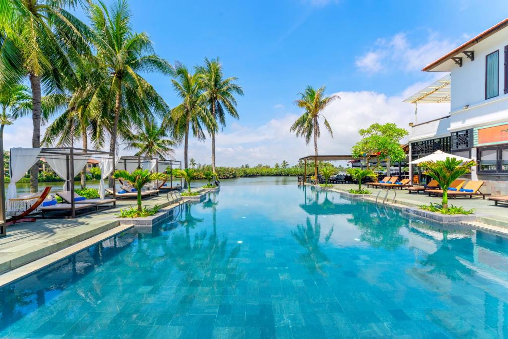 a swimming pool at a resort with palm trees at Hoi An Beach Resort in Hoi An