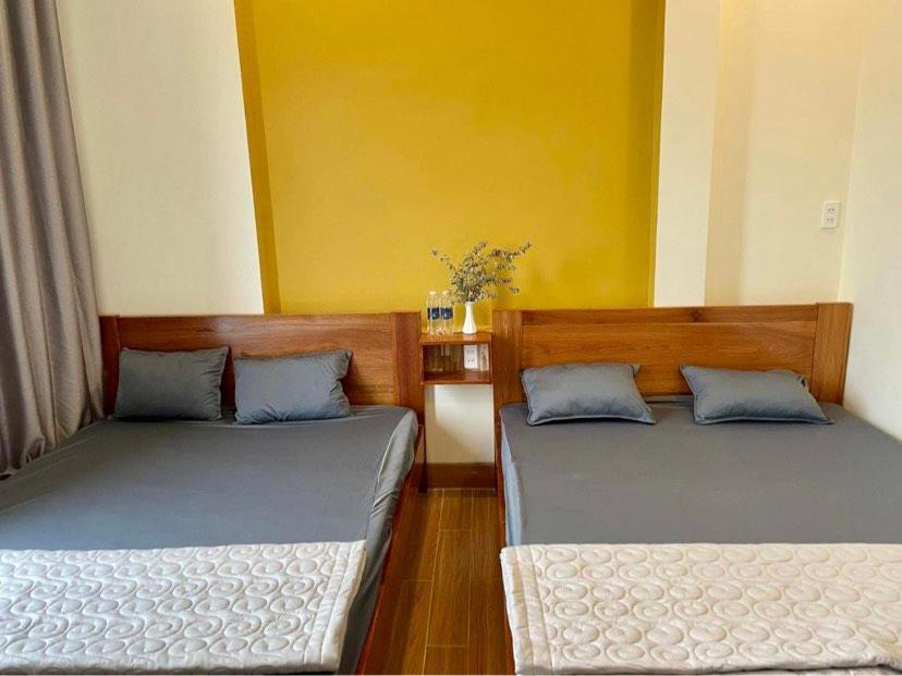 two beds in a room with yellow walls at TRI'S Homestay in Quy Nhon