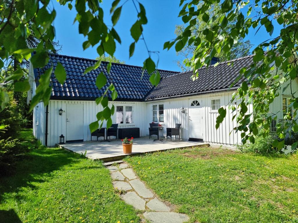 a white house with a patio and a yard at Poeme A SANDEFJORD in Kodal
