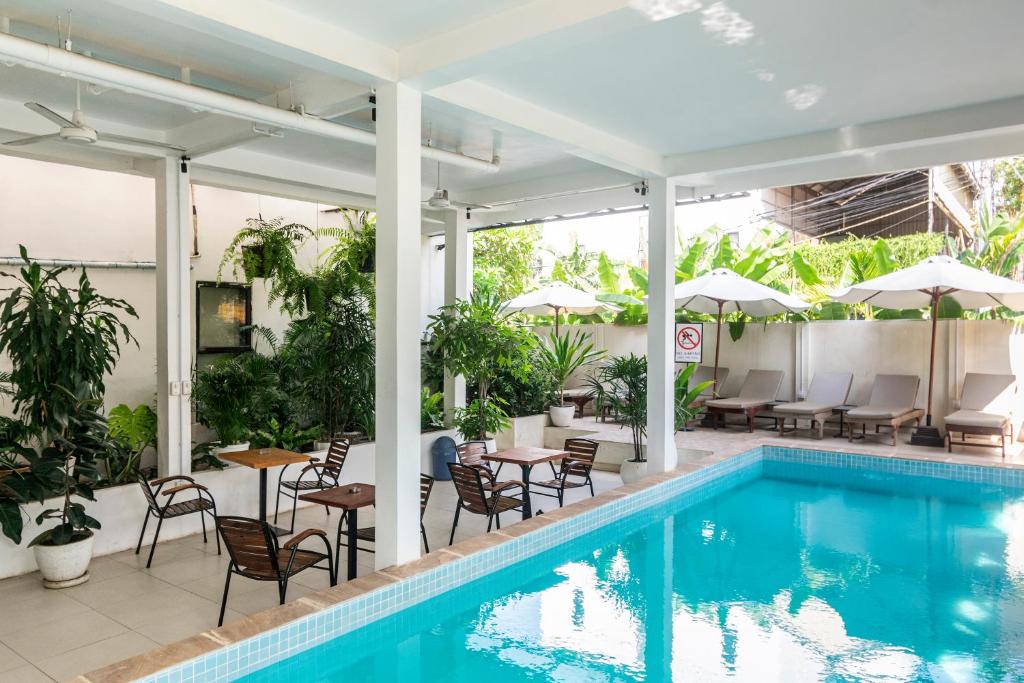 a pool with chairs and tables and umbrellas at Onederz Siem Reap in Siem Reap