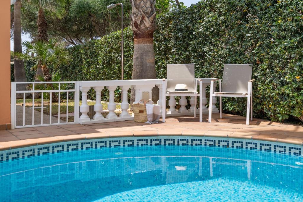 a swimming pool with two chairs next to a fence at Menorca Cristina by Mauter Villas in Cala Blanca