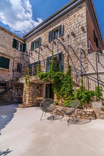 two chairs in front of a brick building with a staircase at Villa Harmony in Supetar