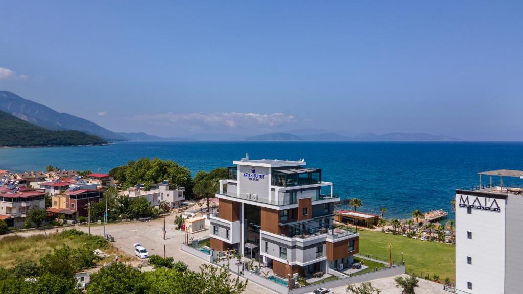 a building in front of the water next to a city at Artan Suites Tatil Evleri in Guzelcamlı