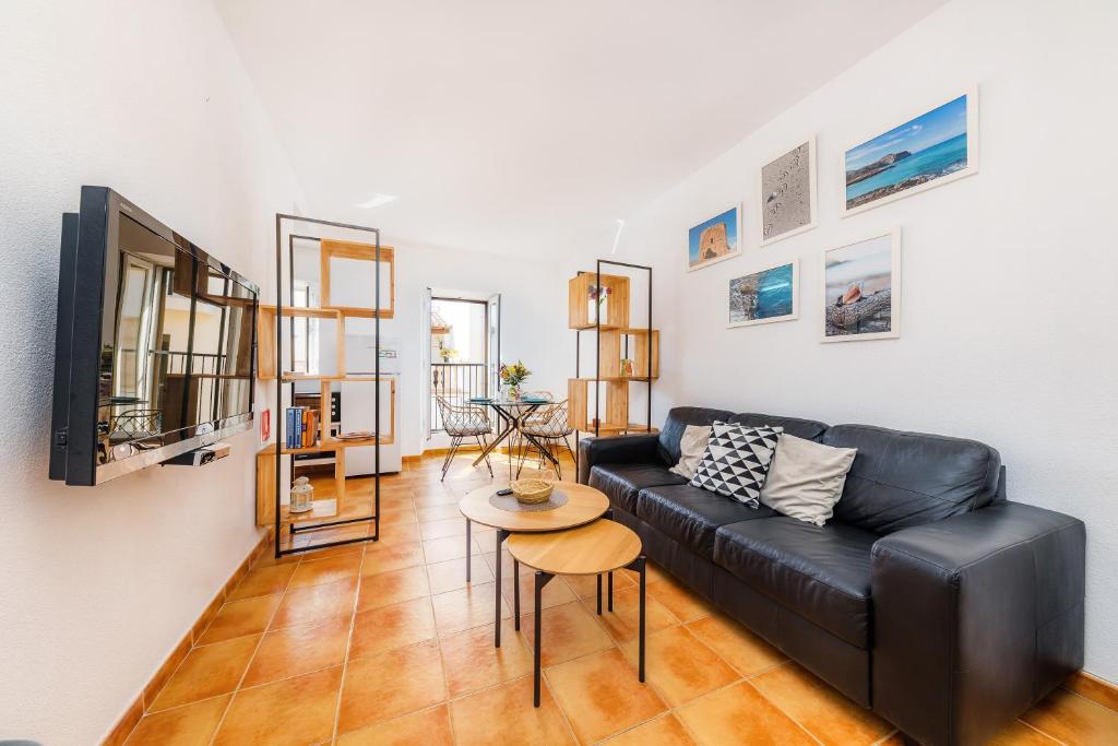 ein Wohnzimmer mit einem schwarzen Ledersofa und einem Tisch in der Unterkunft Casa Jaume A in Artá