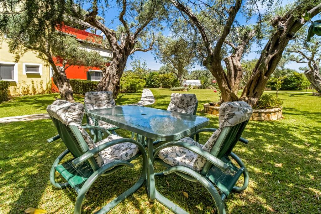 a glass table and four chairs in a yard at Polys Villa Lefkada 1 in Lefkada Town