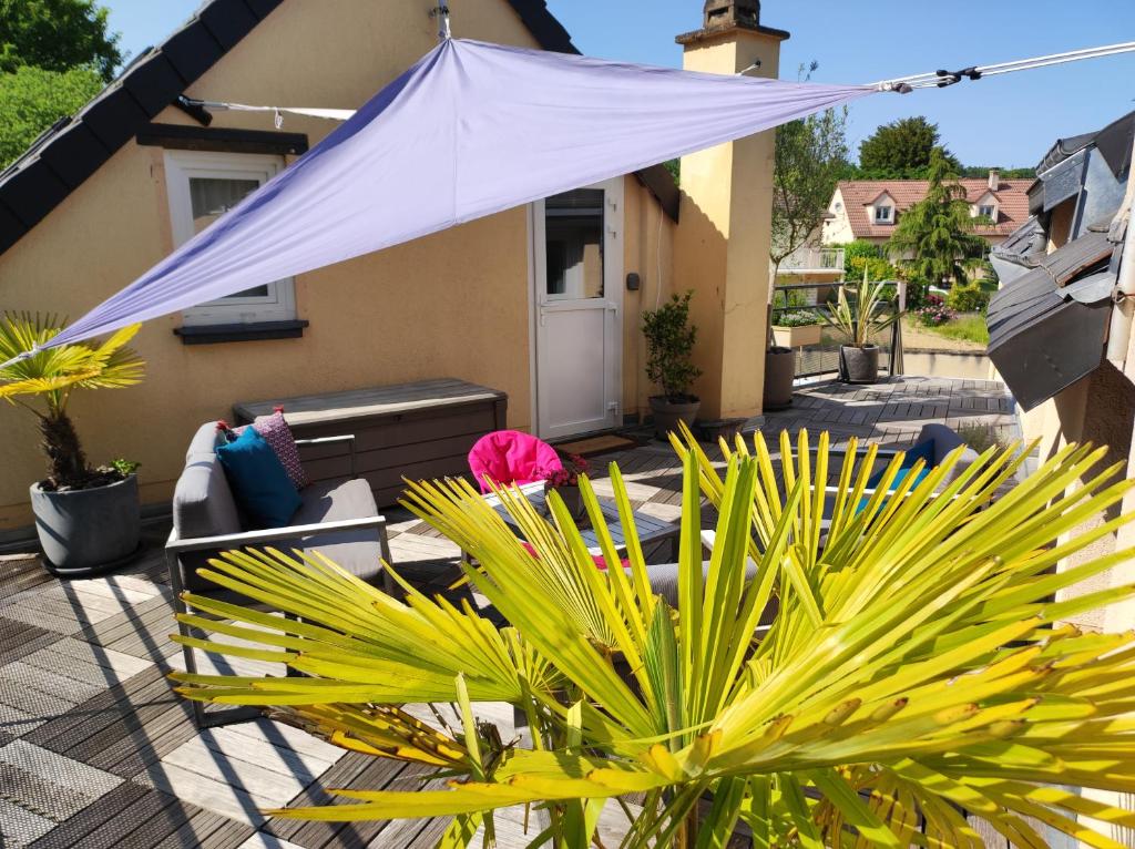 a patio with a purple umbrella and some plants at "Le Rooftop de la fontaine" dans cadre verdoyant in Luisant