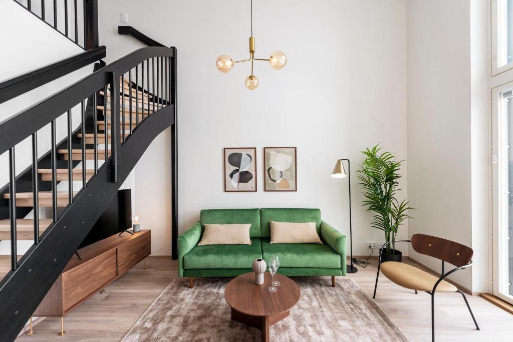 a living room with a green couch and stairs at Loft apartment with lake views in Tampere