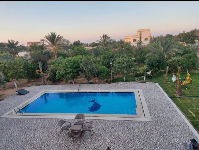 a swimming pool with two chairs and a table at فيلا لوزان الريف الاوروبي in ‘Ezbet Sharikât Wardan