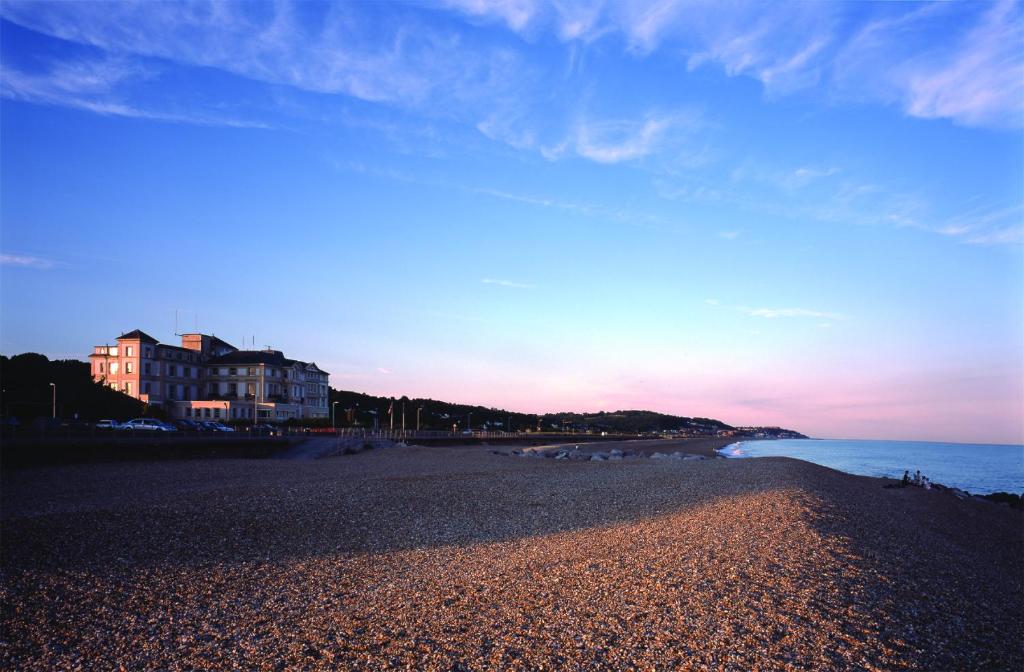 a beach with a building and the ocean at sunset at Prospect Cottage by Bloom Stays in Hythe