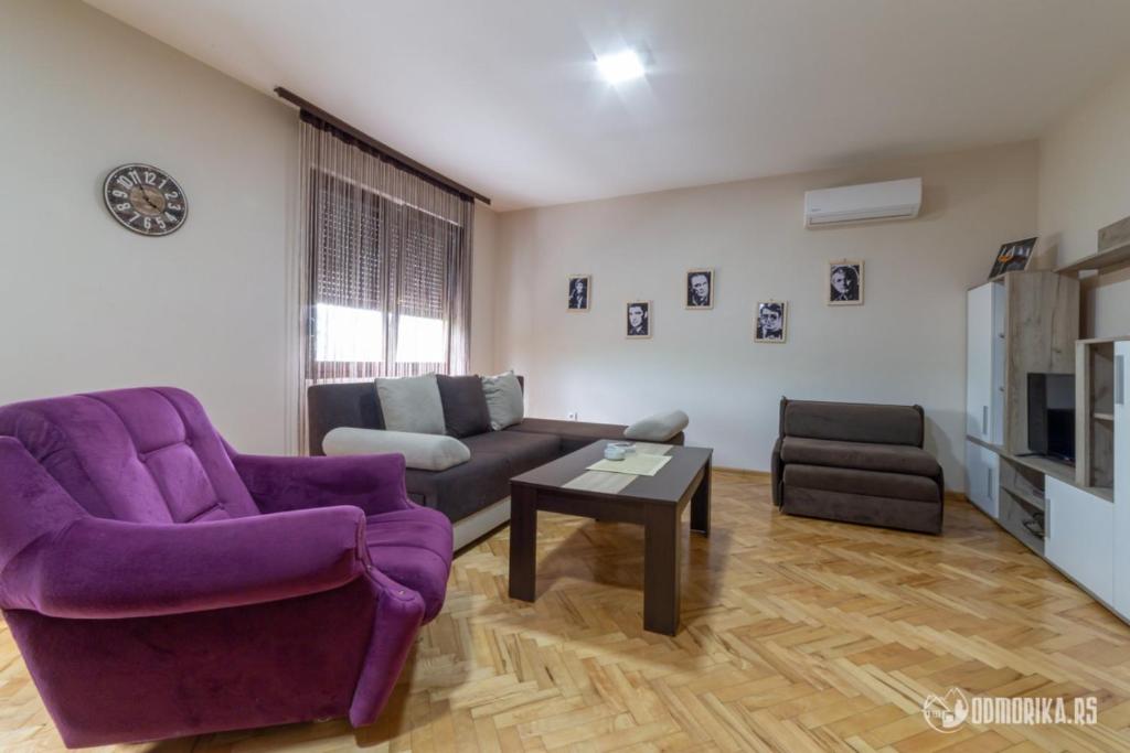 a living room with a purple couch and a table at Apartmani Nina S in Bajina Bašta