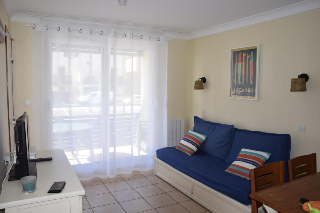 un salon avec un canapé bleu et une télévision dans l'établissement T2 les pieds dans l'eau, mer et piscine, à Lacanau-Océan