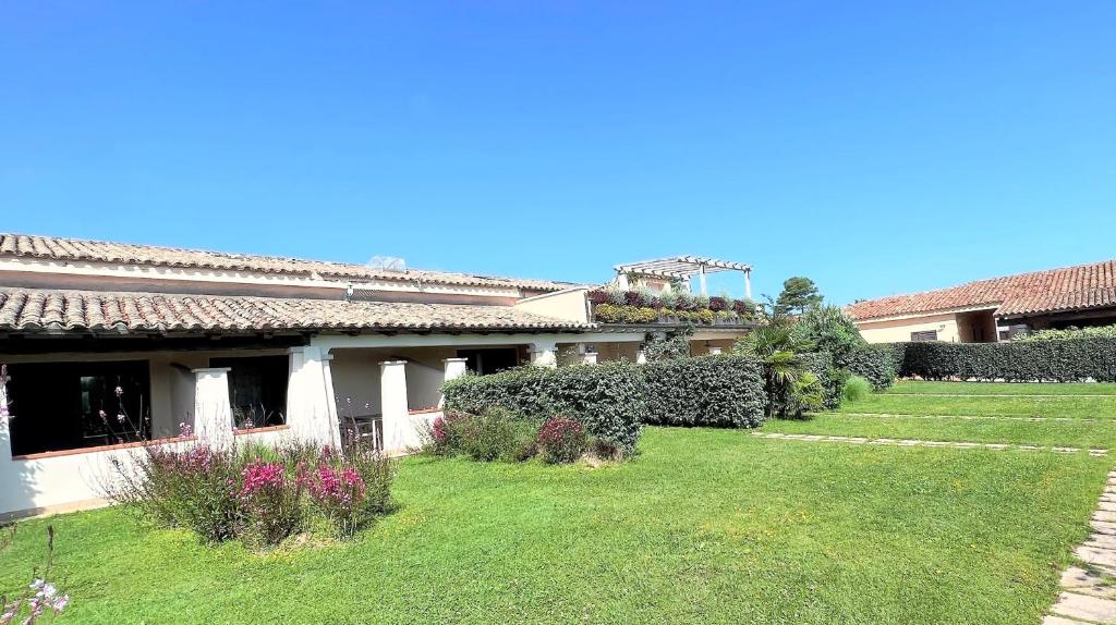 a house with a yard with grass and flowers at ISS Travel, San Teodoro 1 - 100 m from Cala d'Ambra Beach in San Teodoro