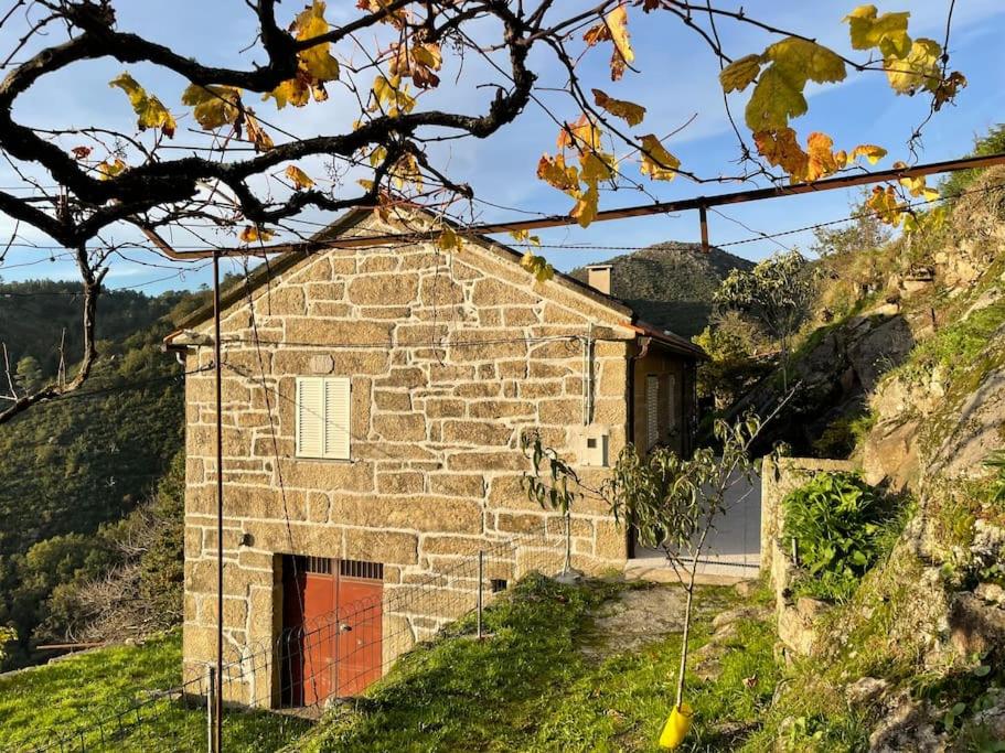 a stone house with a red door on a hill at Casa do Moura in Arcos de Valdevez