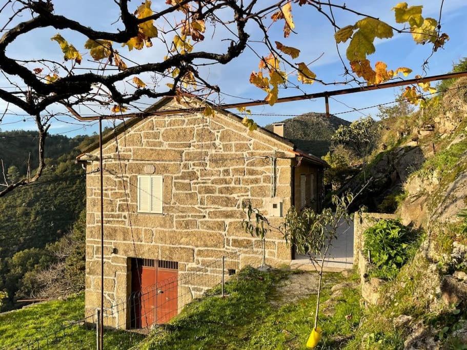 ein Steinhaus mit einer roten Tür auf einem Hügel in der Unterkunft Casa do Moura in Arcos de Valdevez