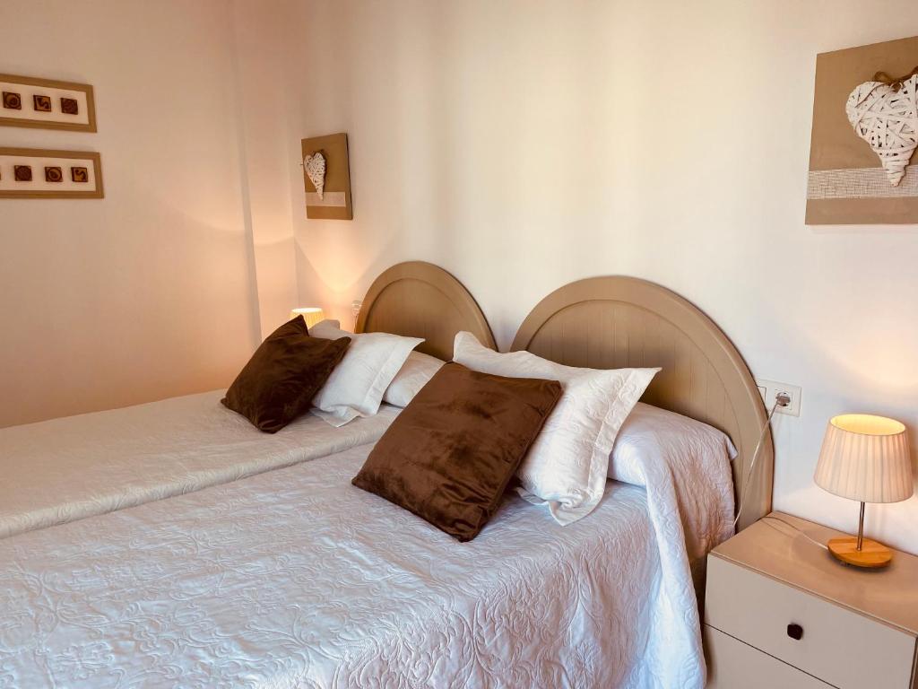 a bedroom with two beds with brown and white pillows at Apartamentos Alcañiz, Silvia in Alcañiz