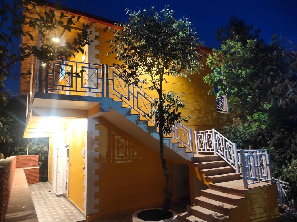 a staircase leading up to a yellow building with a door at Aranya Mukteshwar in Mukteswar