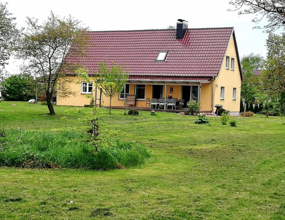 にあるOstseenahes Ferienhaus mit 3 Schlafzimmern und großem Naturgartenの野地の赤屋根の黄色い家
