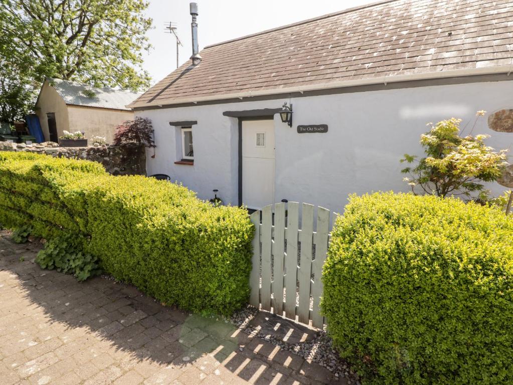 a white house with a fence and bushes at The Old Stable in Haverfordwest