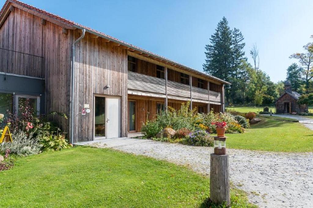 a barn with a garden in front of it at GutsAlm Harlachberg in Bodenmais