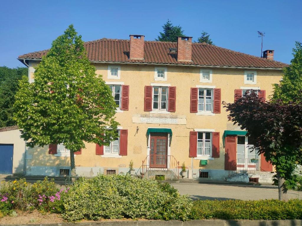 a large house with red shuttered windows and a tree at L'ancienne Gendarmerie in Saint-Laurent-sur-Gorre