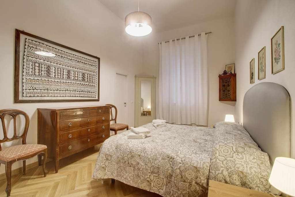 a bedroom with a bed and a dresser and chairs at Piazza Mentana Apartment in Florence