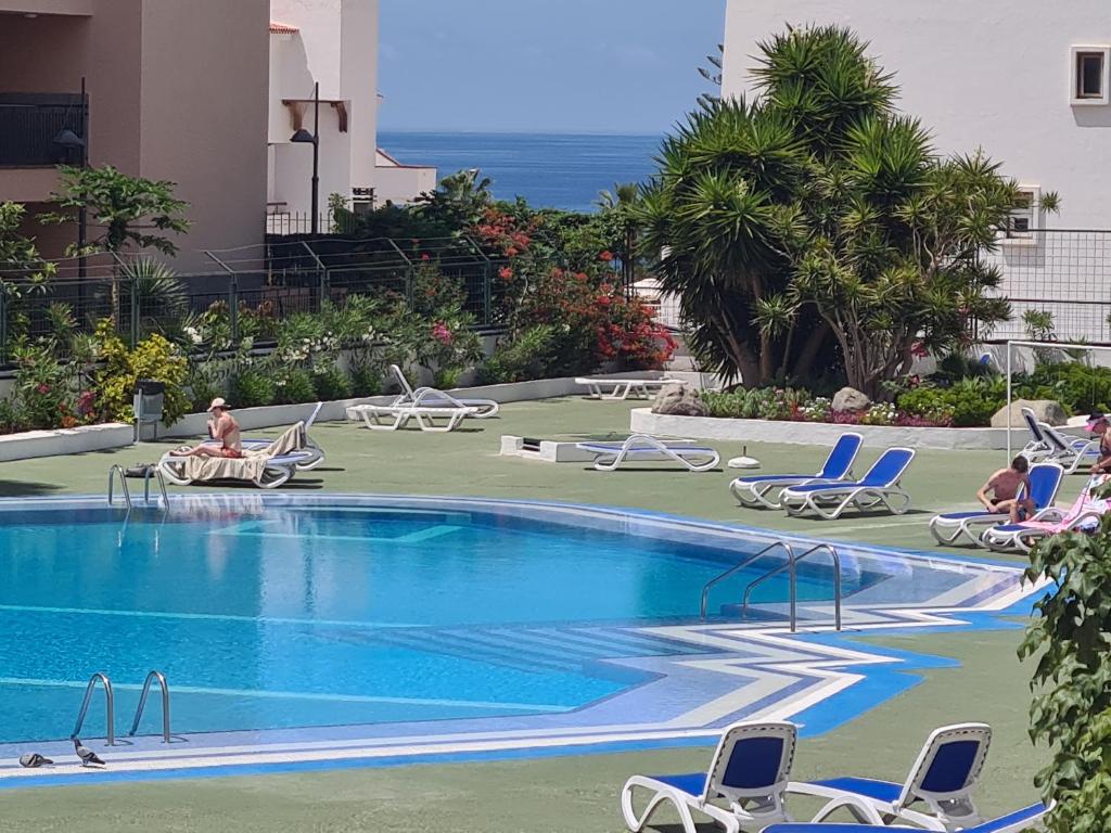 a swimming pool with chairs and people sitting around it at summerland beach in Los Cristianos