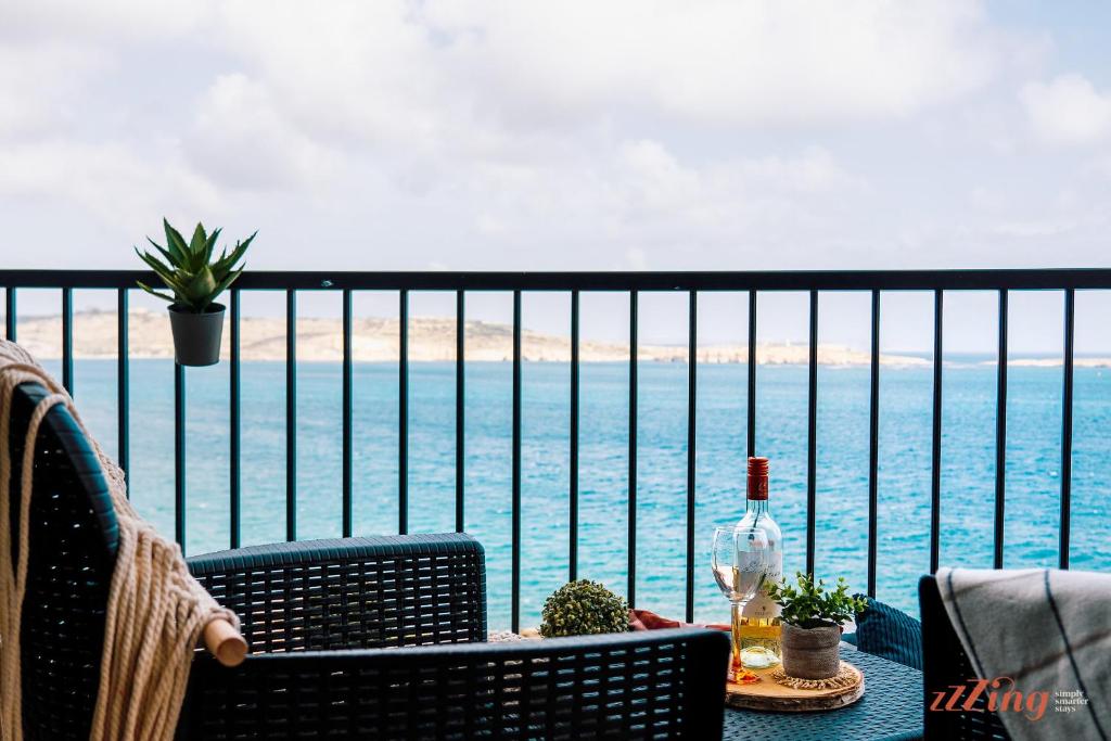 - un balcon avec vue sur l'océan et une bouteille de vin dans l'établissement Stunning Seaviews. Prime Location. Lovely Home., à San Pawl il-Baħar