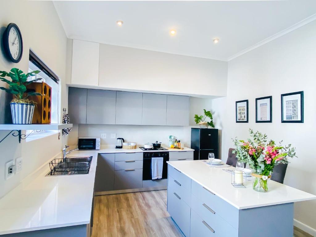 a kitchen with white cabinets and a white counter top at Stay on Main, Family Apartment in Paarl