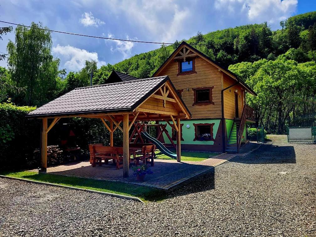 een houten paviljoen met een bank en een huis bij Domek u Bartusia in Wisła