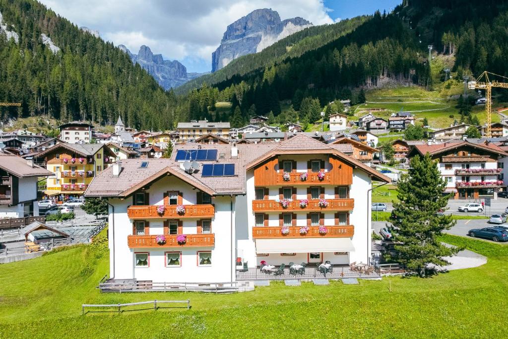 a village in the mountains with a building at Albergo Canazei in Canazei